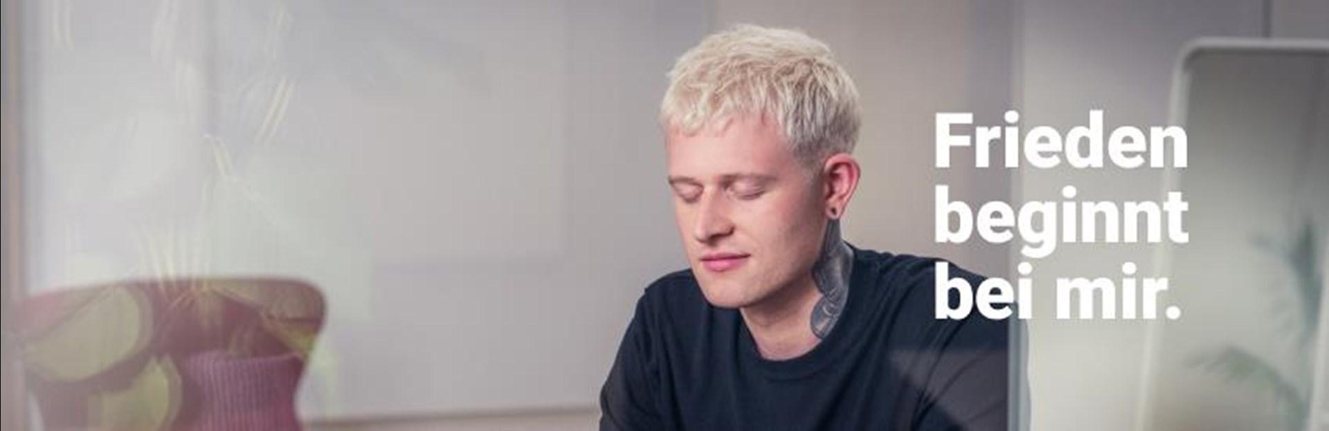 Ein junger Mann mit kurzen blondierten Haaren mit der Aufschrift "Friede beginnt bei mir."